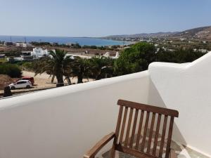 a wooden chair sitting on a balcony overlooking the ocean at Silver Rocks Hotel in Chrissi Akti