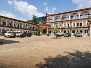 Un gran edificio con coches aparcados en un estacionamiento. en JM Résidence AV NASSER, en Bangui