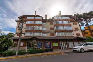 ein Gebäude auf einer Straße mit einem Auto vor der Tür in der Unterkunft Rosa Edifício Parque da Vinícola in Gramado