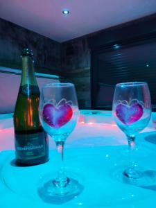 dos copas de vino con corazones pintados al lado de una botella en HORIZON SPA, en Samer