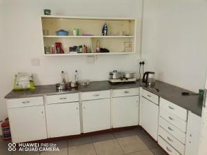 a kitchen with white cabinets and gray counter tops at Sunset Executive Lodge in Boksburg
