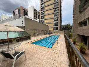 uma piscina com cadeiras e um guarda-sol num edifício em Locking's Funcinários 5 em Belo Horizonte