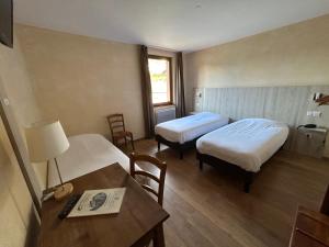 Cette chambre comprend deux lits, une table et un bureau. dans l'établissement Auberge Des Mésanges, à Meisenthal