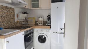 a kitchen with white cabinets and a washer and dryer at Studio La Napoule in Mandelieu-la-Napoule