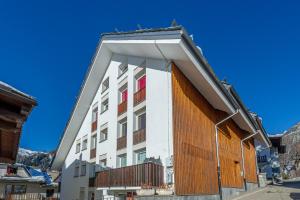 un gran edificio blanco con ventanas rojas y blancas en MAISON ROSE - Relax e vista spettacolare - COUR 0111, en Courmayeur