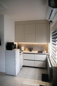 a kitchen with white cabinets and a white refrigerator at Studio Apartman SubUrban in Višnjevac