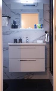 ein weißes Badezimmer mit einem Waschbecken und einem Spiegel in der Unterkunft Studio Apartman SubUrban in Višnjevac