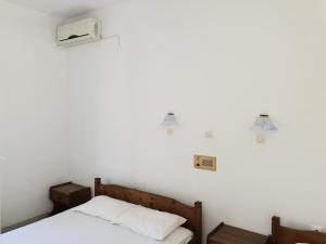 a bedroom with a bed and a white wall at Silver Rocks Hotel in Chrissi Akti