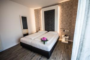 a bedroom with a large bed with a flower on it at Hotel Eden in Torri del Benaco