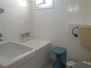 a white bathroom with a blue toilet and a tub at Silver Rocks Hotel in Chrissi Akti