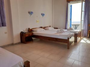 a room with two beds and a window with at Silver Rocks Hotel in Chrissi Akti