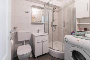 a bathroom with a toilet and a shower and a washing machine at Holiday home Marina-renovated house in city center in Rogoznica