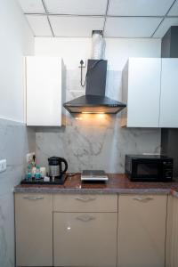 uma cozinha com armários brancos e um forno com placa de fogão em The Lodgers 1 BHK Serviced Apartment Golf Course Road Gurgaon em Gurgaon