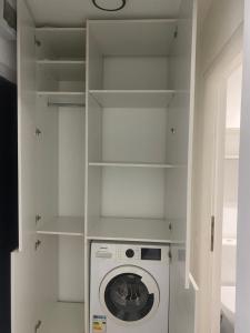 a laundry room with a washing machine and shelves at L&M Apartment in Târgu-Mureş