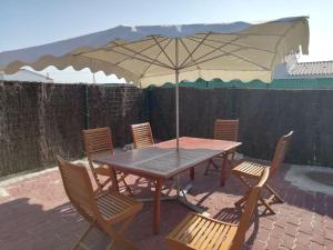 una mesa y sillas con una sombrilla en el patio en Maison au calme à 300m de la plage en La Cotinière