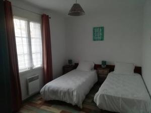 1 dormitorio con 2 camas y ventana en Maison au calme à 300m de la plage en La Cotinière