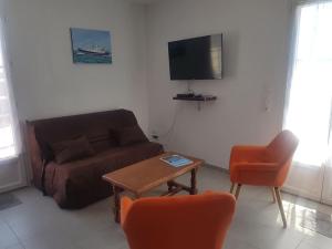 sala de estar con sofá, mesa y TV en Maison au calme à 300m de la plage en La Cotinière