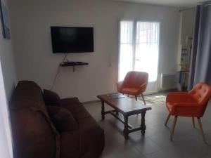 sala de estar con sofá, 2 sillas y TV en Maison au calme à 300m de la plage en La Cotinière