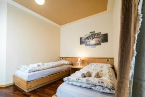 two beds in a room with white walls and wooden floors at Ciasa Gianot in Moena