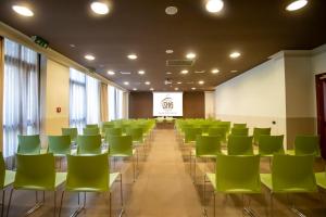 una sala de conferencias con sillas verdes y una pantalla en SHG Hotel De La Ville, en Vicenza