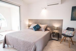 1 dormitorio con 1 cama, 1 silla y 1 ventana en Les Alizés Résidence & Spa en Monticello