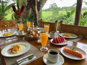 a wooden table with plates of breakfast food and orange juice at MuchoSur Quimbaya in Quimbaya