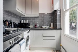 a kitchen with white cabinets and a washer and dryer at CONEN Chert Apartment in London