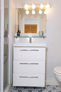 een witte badkamer met een wastafel en een spiegel bij La Mariennée in La Rochelle