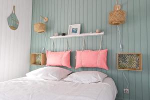 een slaapkamer met een bed met roze en witte kussens bij La Mariennée in La Rochelle
