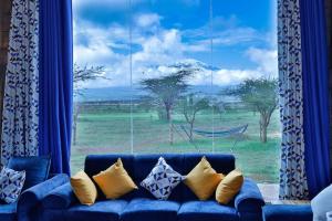 un divano blu di fronte a una grande finestra di Amboseli Glass house a Oloitokitok 