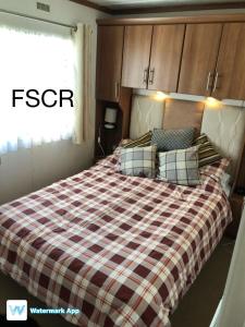 a bedroom with a bed with a plaid blanket at First Steps Caravan Rentals in Sandown