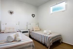 two beds in a white room with a window at Casa Rural El Abuelo in Chiclana de la Frontera +17 photos
