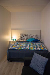 - une chambre avec un lit doté d'une couette colorée et d'un canapé dans l'établissement HighHill Lahti City apartment, à Lahti