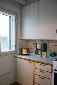 une cuisine avec des placards blancs et un comptoir dans l'établissement HighHill Lahti City apartment, à Lahti