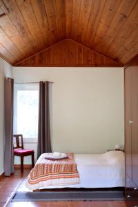 a bedroom with a bed and a wooden ceiling at Casa Cor de Rosa in Madalena