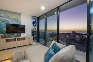 uma sala de estar com grandes janelas de vidro e uma televisão em 200m NEW A Villa with private, heated pool and amazing ocean view em Adeje
