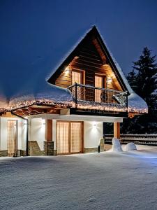 uma casa com varanda na neve à noite em Domki "Na Dziedzinie" z Gorącą Balią em Szaflary