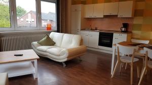 ein Wohnzimmer mit einer weißen Couch und einer Küche in der Unterkunft Ferienwohnungen Brasse in Dornumersiel