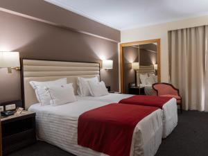 um quarto de hotel com uma cama grande e um cobertor vermelho em Hotel Miracorgo em Vila Real