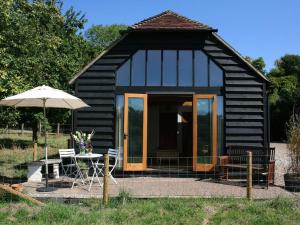 a small black cabin with a table and an umbrella at The Barn At Fishponds in Brook