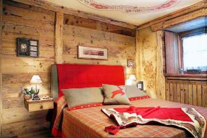 una camera con letto rosso e pareti in legno di La Petite a Courmayeur