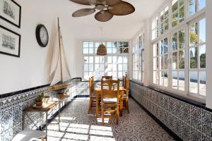 a dining room with a table and chairs and windows at Villa Paraíso in Chiclana de la Frontera