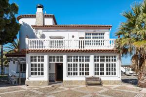 a white house with a balcony and palm trees at Villa Paraíso in Chiclana de la Frontera