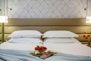 ein Bett mit einer Schale Obst und einem Teller Erdbeeren in der Unterkunft Maxim Design Hotel 3 Star Superior in Tel Aviv