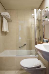 a bathroom with a shower and a toilet and a tub at Maxim Design Hotel 3 Star Superior in Tel Aviv
