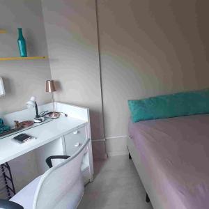 um quarto com uma secretária branca e uma cama em Apartamento pé na areia Praia do Gonzaguinha. em São Vicente