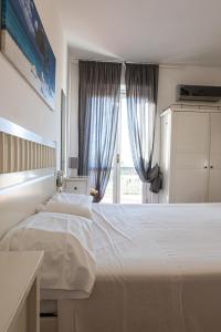 a bedroom with a large white bed and a window at Gambero Nero in Tellaro