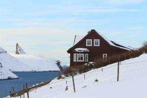 a house on a hill in the snow at Cosy groundfloor apartment in Sørvágur