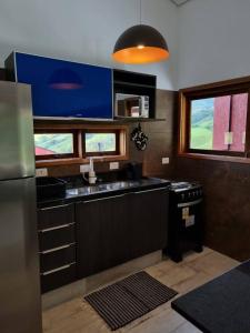 eine Küche mit Herd und Kühlschrank in der Unterkunft La Trinca Casas Charmosas in São Bento do Sapucaí
