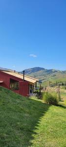 ein rotes Haus auf einem Hügel mit einem grünen Feld in der Unterkunft La Trinca Casas Charmosas in São Bento do Sapucaí + 32 Fotos